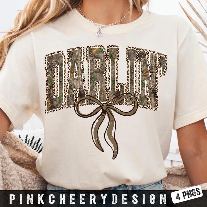 May include: Cream-colored t-shirt with the word "DARLIN" in a camouflage and leopard print design. A brown bow is centered below the word. The text "PINKCHEERYDESIGN 4 PNGS" is at the bottom.