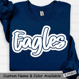 May include: A navy blue sweatshirt with the word "Eagles" in white, outlined in navy blue. The text "Custom Name & Color Available" is at the bottom. The sweatshirt has a crew neck and long sleeves.