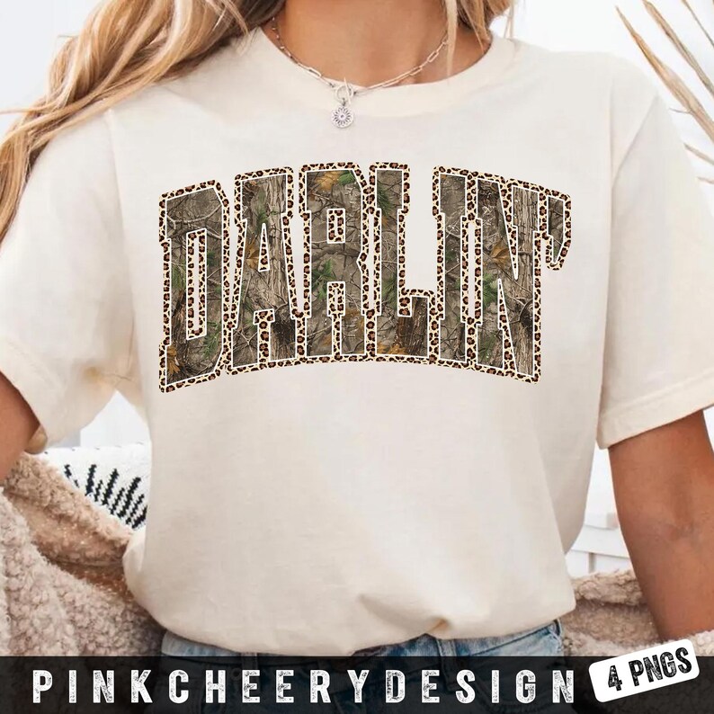 May include: Cream-colored t-shirt featuring the word "DARLIN" in a bold, block letter design. The letters are filled with a camouflage pattern and outlined with a leopard print. The text "PINKCHEERYDESIGN 4 PNGS" is at the bottom.