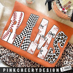 May include: An orange t-shirt with the word "RAMS" in a variety of patterns. The "R" is designed like a baseball, the "A" has a black and white checkered pattern, the "M"s have baseballs and bows, and the "S" has a leopard print.