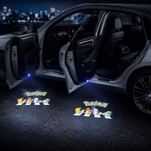 May include: A silver car with open doors featuring LED door projectors that cast a bright, colorful light onto the ground. The projection displays the Pokémon logo above four characters walking in a line, mimicking a classic crosswalk scene.