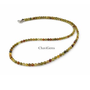 May include: A necklace featuring small, round beads in shades of green, brown, and red. The beads are strung together to form a necklace with a silver clasp. The image includes the text "ChaviGems".