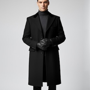 Puede incluir: Un abrigo largo negro con cuello de terciopelo, usado sobre un cuello alto gris y guantes negros. El abrigo está abotonado y combinado con pantalones y zapatos negros. El conjunto es formal y sofisticado.