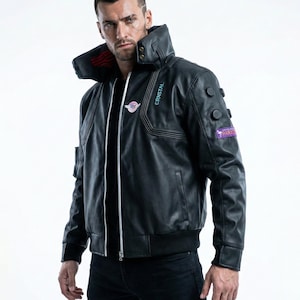 May include: Black leather jacket with a high collar and multiple patches. The jacket features a zipper closure and ribbed cuffs and hem. Patches include the text "CRNSTAL" and "PARADISE".