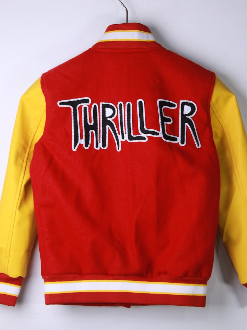 May include: Red and yellow varsity jacket with the word "THRILLER" in black and white lettering across the back. The jacket has yellow sleeves, a red body, and white and yellow striped trim.