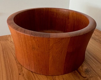 May include: A large, round, wooden bowl with a dark brown color. The bowl is made of natural wood and has a smooth, polished finish.