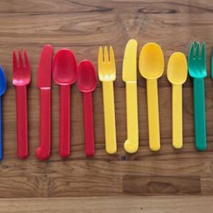 May include: A set of 12 plastic utensils in blue, red, yellow, and green. The set includes forks, spoons, and knives.
