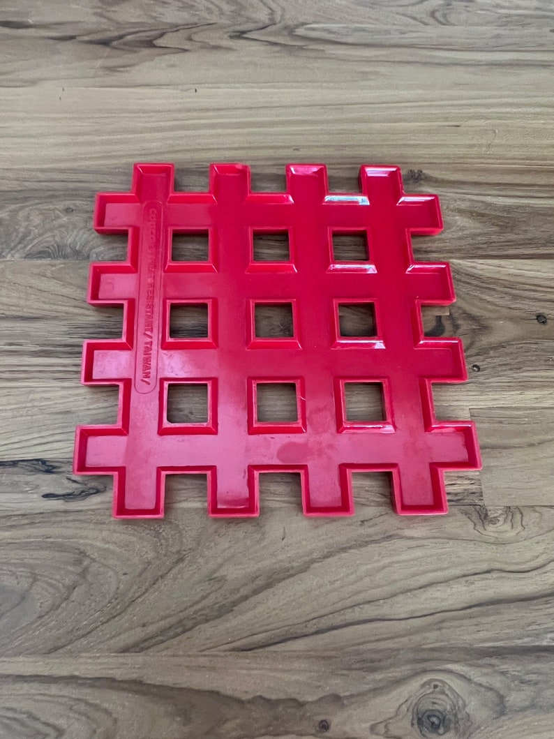 May include: A bright red plastic grid with square holes. The grid is made of interlocking pieces and has the text "Copyright 1983/1987/Taiwan" printed on the side.