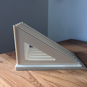 May include: A white plastic bread rack with a triangular design. The rack has multiple slots for holding bread.