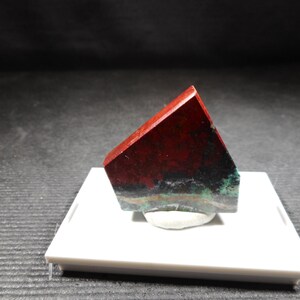May include: A triangular piece of red, green, and black jasper with a smooth, polished surface.