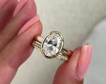 Conjunto de noivado com diamante moissanita de corte oval, em ouro amarelo maciço 9K, com aliança cravejada em canal e anel solitário com cravação em garras.