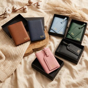 May include: A collection of passport holders and luggage tags in brown, navy blue, light blue, green, black, and pink. Each item features a textured finish and the gold-embossed initials SH. The items are presented in black boxes.
