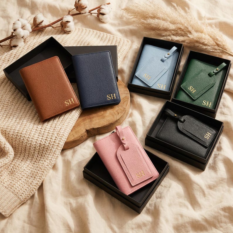 May include: A collection of passport holders and luggage tags in brown, navy blue, light blue, green, black, and pink. Each item features a textured finish and the gold-embossed initials SH. The items are presented in black boxes.
