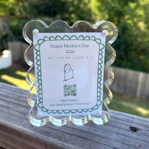 May include: Clear acrylic picture frame with a scalloped edge, holding a card that reads "Happy Mother's Day 2026" with a drawing and the text "Open when... you need to hear 'I love you'".