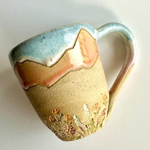 May include: A white ceramic mug with a black handle and the text "But First, Coffee" in a handwritten style. The mug is likely 11-15 ounces, perfect for a morning beverage.