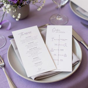 Puede incluir: Un plato blanco con una servilleta gris contiene dos tarjetas impresas. Una tarjeta dice "The Menu" y enumera aperitivos, entrantes, plato principal, postres y bocadillos nocturnos. La otra tarjeta es una línea de tiempo de "Orden de eventos".