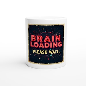 Może przedstawiać: Biały ceramiczny kubek z napisem "BRAIN LOADING PLEASE WAIT.." w czerwonych i żółtych literach. Projekt przedstawia grafikę mózgu i ciemne tło z kolorowymi rozbłyskami. Kubek ma standardowy uchwyt.