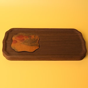 May include: A dark brown wooden serving tray with a decorative edge. A small, irregularly shaped coaster with orange, brown, and green tones sits on the tray. The tray and coaster are set against a yellow background.