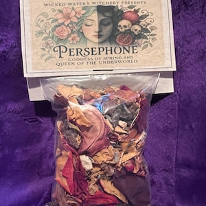 May include: A clear plastic bag filled with dried flowers and herbs, with a decorative label. The label reads "Wicked Waters Witchery Presents Persephone Goddess of Spring and Queen of the Underworld" with floral and skull illustrations.