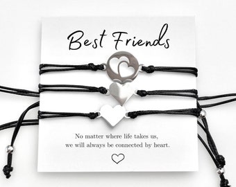 May include: Set of four black friendship bracelets with silver heart charms. The bracelets have adjustable closures and are packaged on a white card with the text "Best Friends" and a quote about being connected by heart.