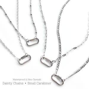 May include: Several silver-colored necklaces with small carabiner clasps are displayed against a white background. The chains have various delicate designs. Text at the bottom reads "Waterproof & Non-Tarnish. Dainty Chains • Small Carabiner."