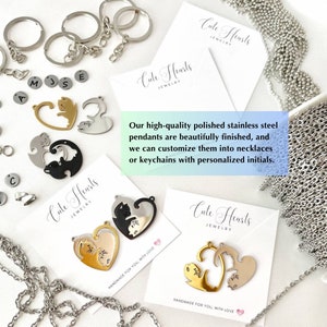 May include: Two silver chains, a gold chain, and a silver chain with a silver charm. The charm is a heart with two cats inside. The charm is on a white card with the text 'Cute Hearts Jewelry' and 'Handmade for you, with love.' The card is on a white surface with other charms and chains.