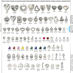 May include: A collection of silver-toned metal charms in various shapes including hearts, keys, and padlocks, arranged in rows with alphanumeric codes. A one-inch ruler is visible on the right side for scale. The charms feature diverse finishes.