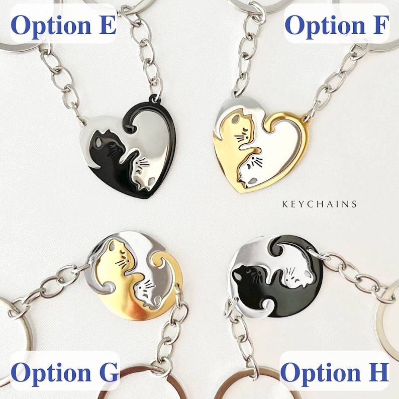 May include: Four different keychain options featuring two cats in a yin yang design. Option E and F are heart-shaped keychains. Option E is black and silver, and Option F is gold and silver. Option G and H are round keychains. Option G is gold and silver, and Option H is black and silver. The text 'KEYCHAINS' is visible below the keychains.
