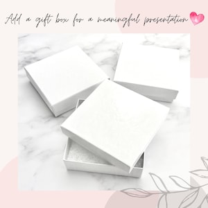 May include: Three white gift boxes on a white marble surface. One box is open and shows a white foam interior. The text 'Add a gift box for a meaningful presentation' is above the boxes.