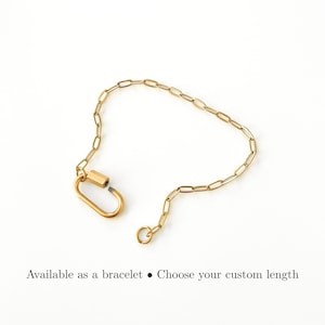 May include: A gold-toned chain bracelet featuring elongated oval links and a large, functional carabiner-style clasp. The text below the jewelry reads: Available as a bracelet &bull; Choose your custom length. The design is simple and metallic.
