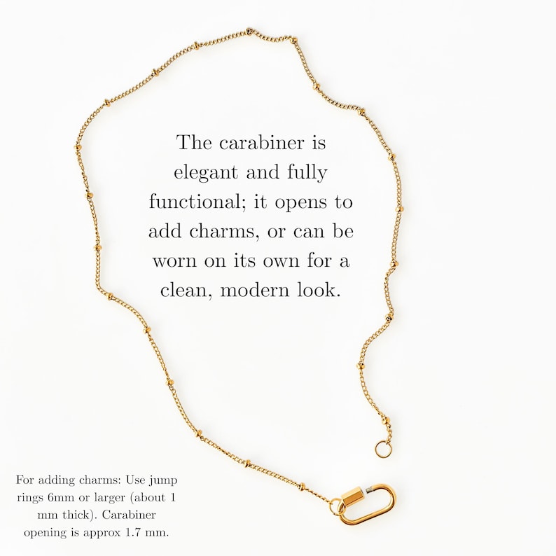 May include: A gold-toned chain necklace featuring small evenly spaced beads and a functional carabiner clasp. The text reads: The carabiner is elegant and fully functional; it opens to add charms, or can be worn on its own for a clean, modern look. For adding charms: Use jump rings 6mm or larger (about 1 mm thick). Carabiner opening is approx 1.7 mm.