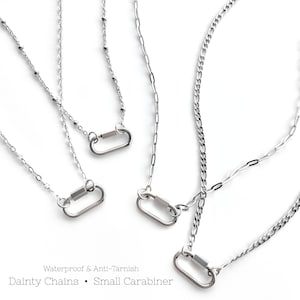 May include: Multiple silver necklaces with small carabiner pendants are shown against a white backdrop. The necklaces have delicate chains in different designs. Text on the image reads: "Waterproof & Anti-Tarnish. Dainty Chains • Small Carabiner."