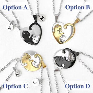 May include: Four sets of matching necklaces with a cat design. Option A has a black and white cat design with a silver chain and the letter A charm. Option B has a gold cat design with a silver chain and the letter M charm. Option C has a gold cat design with a silver chain and the letter K charm. Option D has a black and white cat design with a silver chain and the letter J charm.