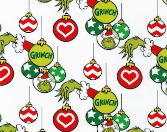 May include: White fabric with a repeating pattern of Christmas ornaments and Grinch elements. The ornaments include red hearts, green stars, and Grinch faces. The Grinch's arm and hand are also featured.