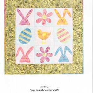 May include: A quilt pattern for an Easter 9-patch quilt. The pattern features a 3x3 grid of colorful Easter-themed images, including bunnies, chicks, eggs, and flowers. The quilt is 21 inches by 21 inches.