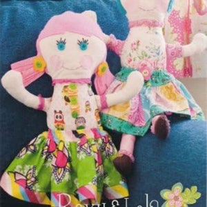 May include: Two handmade rag dolls, Roxy & Lola, with colorful fabric clothing. The dolls have painted faces and are sitting on a blue couch. The image includes the text "Roxy & Lola Ragdolls No. 29".