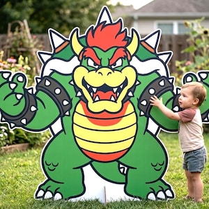Könnte beinhalten: Ein großer, grüner Bowser-Ausschnitt mit roten Haaren, gelbem Bauch und Stachelarmbändern steht in einem grasbewachsenen Garten. Ein junges Kind in einem braunen und weißen Hemd und blauen Shorts greift nach dem Ausschnitt. Der Ausschnitt ist ein lustiges, dekoratives Objekt.