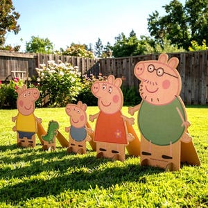 Puede incluir: Figuras de cartón de los personajes de Peppa Pig, incluyendo a Peppa, George, Mamá Pig y Papá Pig, y un dinosaurio. Las figuras están colocadas sobre un césped verde frente a una valla de madera. Los personajes visten trajes coloridos.