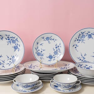 Puede incluir: Una taza de cerámica blanca con un asa negra y el texto "But First, Coffee" en negro, con una fuente de estilo manuscrito. La taza está sobre una superficie blanca.