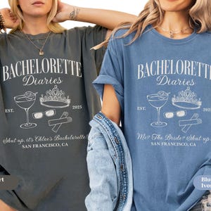 May include: Two t-shirts, one pepper-colored and one blue, each with a white graphic. The graphic includes the text "BACHELORETTE Diaries" with a cocktail, crown, sunglasses, and gloves. The text "Shut up, it's Chloe's Bachelorette!" and "Me? The Bride? Shut up!" are also included.