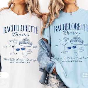 May include: Two t-shirts, one white and one light blue, with a navy blue graphic. The graphic includes the text "BACHELORETTE Diaries", a cocktail, a crown, sunglasses, gloves, and the text "SAN FRANCISCO, CA".