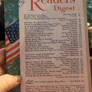 Może przedstawiać: Vintage wydanie magazynu Reader's Digest z lipca 1967 roku. Okładka zawiera tytuł w dużych czerwonych literach, z małą grafiką amerykańskiej flagi. Magazyn jest trzymany przez osobę.