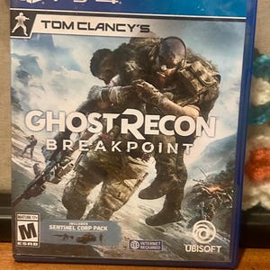 Puede incluir: Caja de juego de PS4 para Tom Clancy's Ghost Recon Breakpoint. La portada muestra a dos soldados con equipo de combate, ambientados en un fondo montañoso y nublado. El juego está clasificado como Mature 17+ por ESRB.