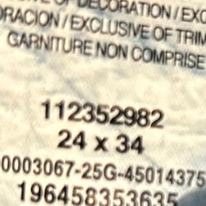 以下が含まれることがあります： 黒い文字が書かれた白いラベルのクローズアップ。 ラベルには、数字の112352982と寸法24 x 34が含まれています。 1000003067-25G-4501437537や196458353635など、追加のテキストと数字も表示されます。