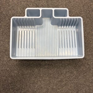 May include: A light blue plastic dish drying rack featuring a rectangular base with vertical ridges for plate organisation and two integrated compartments at the top for cutlery storage. The structure has a raised back section and a smooth rim.