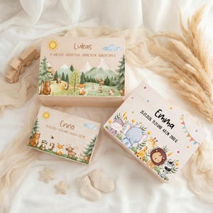 Könnte beinhalten: Drei Holz-Andenkenboxen mit Illustrationen von Wald- und Dschungeltieren. Die Boxen sind mit Namen, Daten, Uhrzeiten und Maßen personalisiert. Die Maße sind in Zentimetern und Gramm.