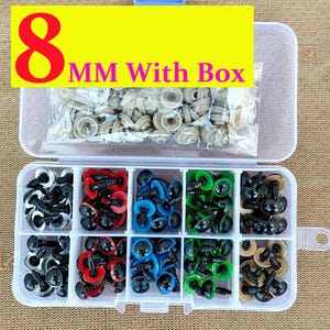 May include: A clear plastic organizer box filled with various colored craft eyes. The box contains black, red, blue, green, and tan eyes, along with a bag of tan eyes. The text "8 MM With Box" is displayed on a yellow banner.