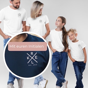 May include: A family of four wearing matching white t-shirts with a small black graphic on the chest. The shirts have a navy blue graphic with the initials "RKE" and the text "EST. 2023". The family is wearing blue jeans.