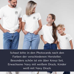 May include: Four people wearing matching white t-shirts and blue jeans. Each shirt has a small black graphic on the chest. The text on the image reads, "Schaut bitte in den Photocards nach den Farben der verschiedenen Hersteller."