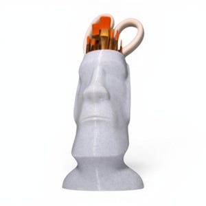 May include: A light grey, speckled Moai head-shaped desk organiser holding several paintbrushes with bright orange bristles and a pair of light-coloured scissors. The organiser features a stylised human face with a prominent nose and chin.